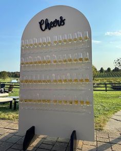 a sign with glasses on it that says cheers in front of a picnic table and benches