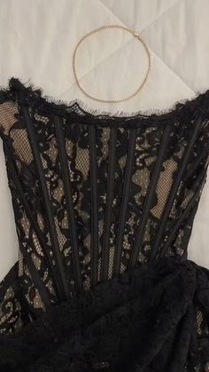 a black dress with lace on it and a choker necklace hanging from the neck