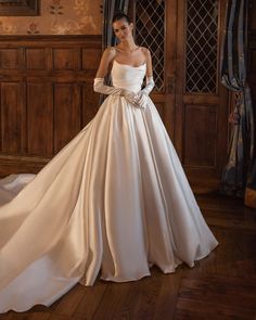 a woman in a wedding dress standing on a wooden floor