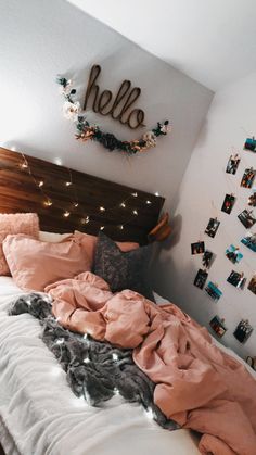 an unmade bed with pink sheets and blankets on it in front of a hello sign