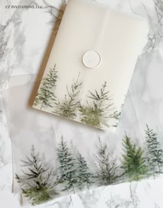 an envelope with trees printed on the front and inside, sitting on top of marbled paper