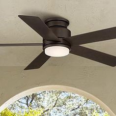 a ceiling fan that is mounted on the outside of a house with trees in the background