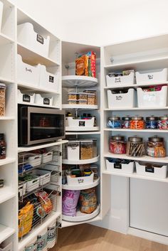 an organized pantry with white shelving and lots of food in bins on the shelves