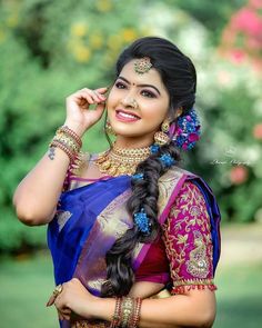 a woman in a blue and pink sari with braids on her head, smiling