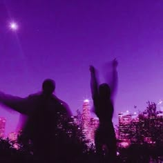 two people standing in front of a city skyline with their arms up and hands raised