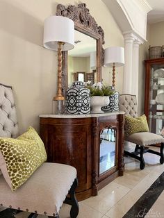 a living room filled with furniture and a mirror on top of a table next to a chair