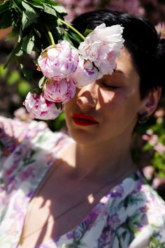 a woman with flowers in her hair is looking at the camera while she has her eyes closed