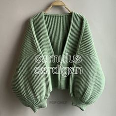 a green sweater hanging on a hanger with the words cumulus cardigan written below it