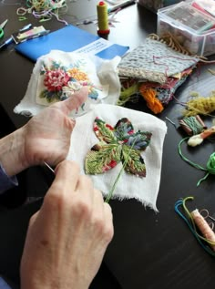 a person is working on some embroidered items