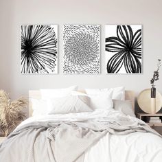 three black and white paintings on the wall above a bed