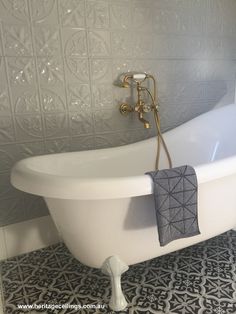 a white bath tub sitting on top of a black and white tiled floor next to a wall