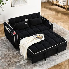 a black futon sofa bed sitting on top of a rug in a living room