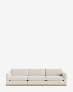 a white couch sitting on top of a wooden table in front of a white wall