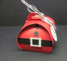 a small red box with a santa hat on it's side and a tag hanging from the top