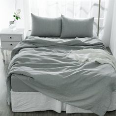 an unmade bed in a bedroom with white walls