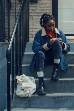 a woman sitting on the steps looking at her cell phone