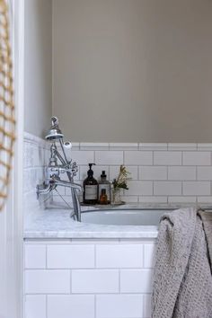 a bathroom with white subway tile and gray walls, along with a bathtub in the corner