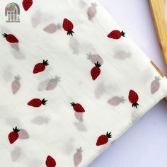 the fabric has strawberries on it and is next to a pair of wooden scissors