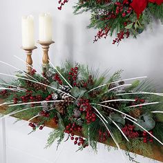 two christmas wreaths on a mantle with candles