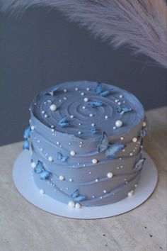 a blue cake sitting on top of a white plate next to a tall gray feather