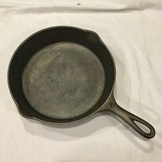 an old cast iron skillet on a white tablecloth with the handle extended to it