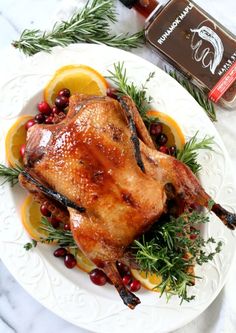 a whole chicken on a plate with cranberries and lemons next to it