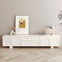 a white entertainment center with an art print on the wall