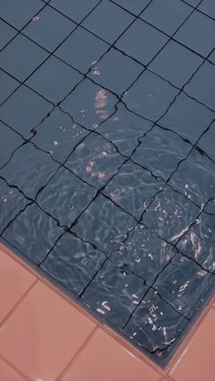 the surface of a swimming pool with water reflecting off it's sides and tiles on the floor