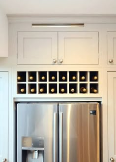 a stainless steel refrigerator freezer sitting inside of a kitchen next to white cupboards