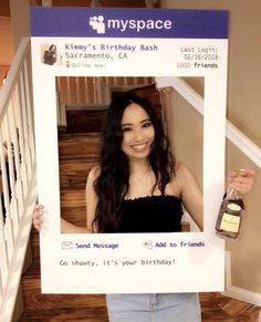 a woman holding up a birthday card with a bottle of whiskey in front of her