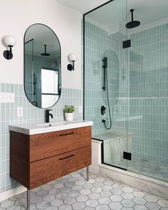 a bathroom with a sink, mirror and stand up shower stall in it's corner