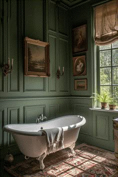 an old fashioned bathtub in the corner of a room with green walls and pictures on the wall