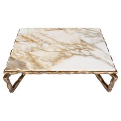 a white marble coffee table with brass legs and an intricate design on the top, against a white background