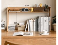 a desk with books, camera and other items on it next to a wall mounted clock