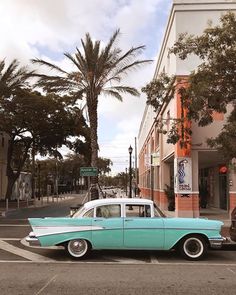 an old blue and white car parked in front of a building on a street corner