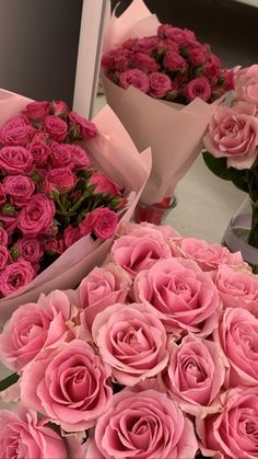 many pink roses are arranged on a table with other flowers in vases behind them