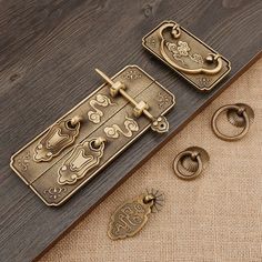 two brass door handles on top of a wooden floor next to some metal rings and hooks