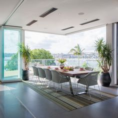 a dining room table and chairs in front of a large window with the view of water