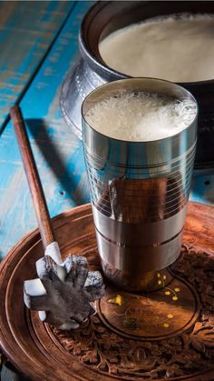 a wooden tray with a metal cup filled with liquid and ice cubes on it