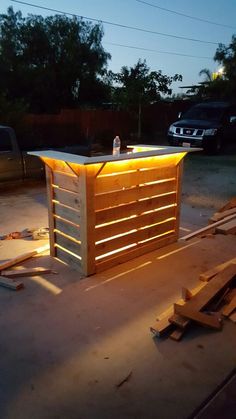 an outdoor bar made out of pallets and wooden planks with lights on it