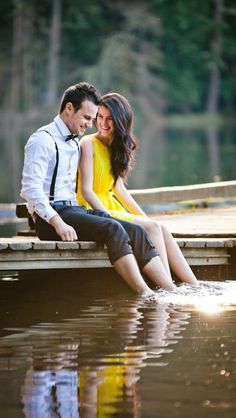 a man and woman sitting on a dock in the water