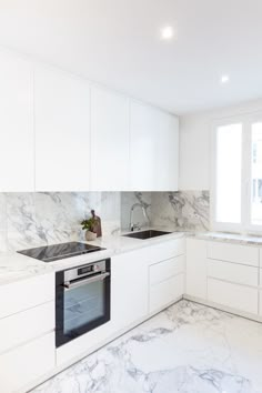 a kitchen with marble counter tops and white cabinets, along with a stove top oven