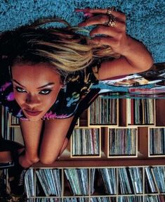 a woman laying on top of a shelf filled with cds