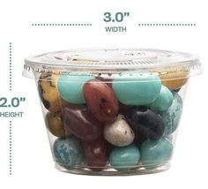 a plastic container filled with lots of different colored rocks next to a measuring scale showing the height of each item