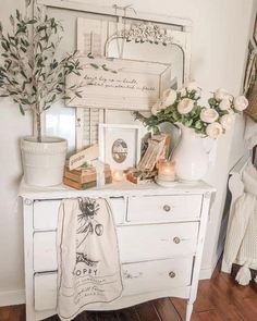 a white dresser with flowers and candles on it