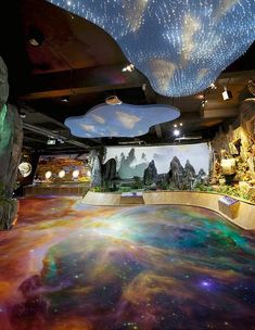 a room filled with lots of colorful lights and paintings on the wall above it is an indoor swimming pool