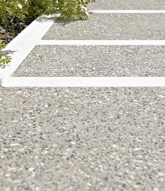 an empty parking lot with white lines painted on the pavement and plants growing out of it