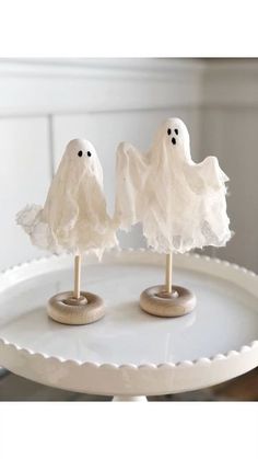 two marshmallows with ghost faces on them are sitting on a white tray