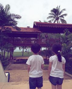 two young children are standing in front of a gazebo with palm trees behind them