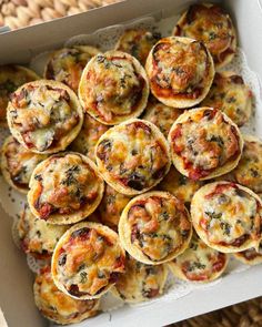 a box filled with mini pizzas sitting on top of a table